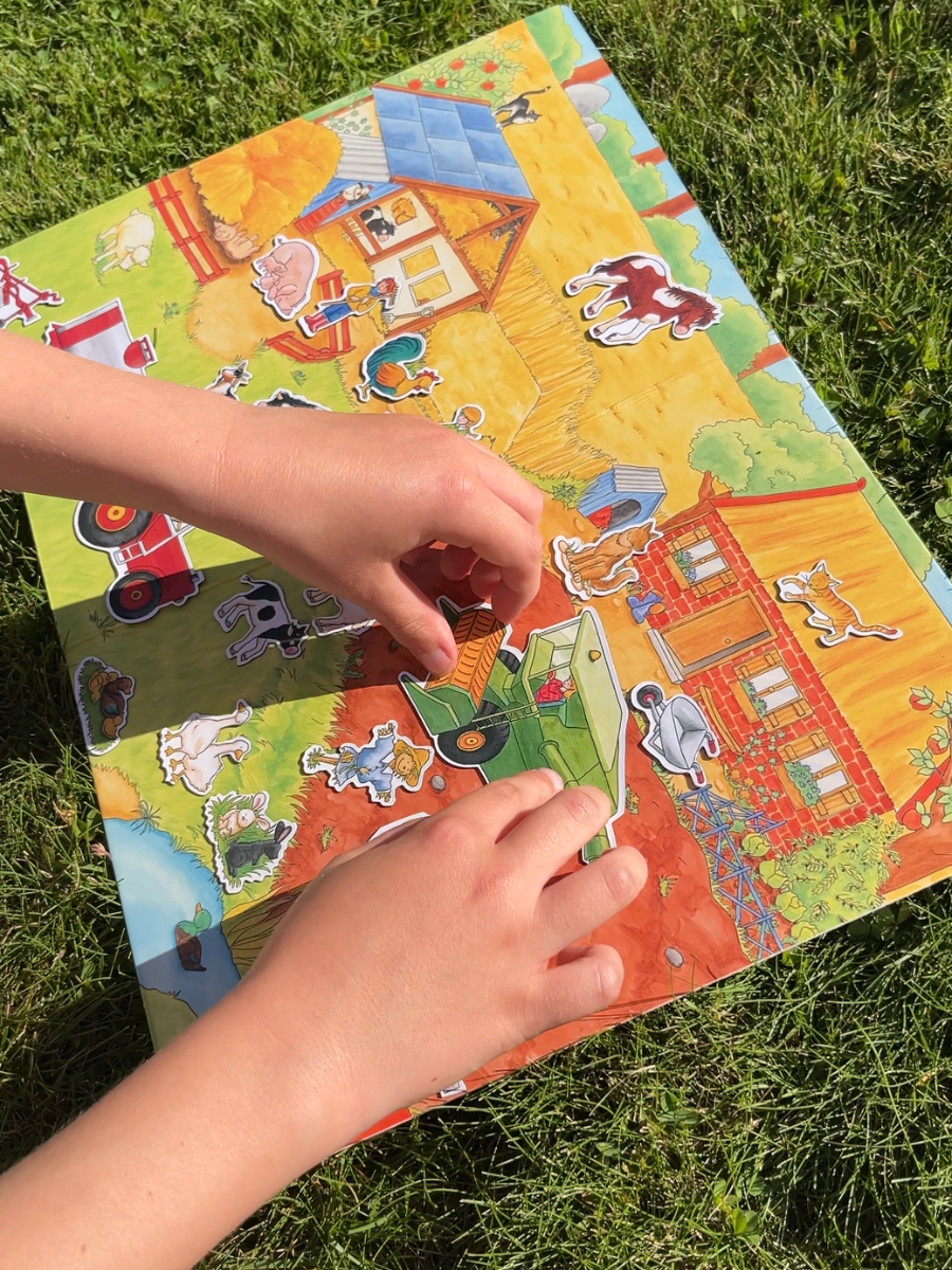 Barnehander som leker med "Livet på bondegården". Brikkene er magnetiske og kan enkelt flyttes rundt.