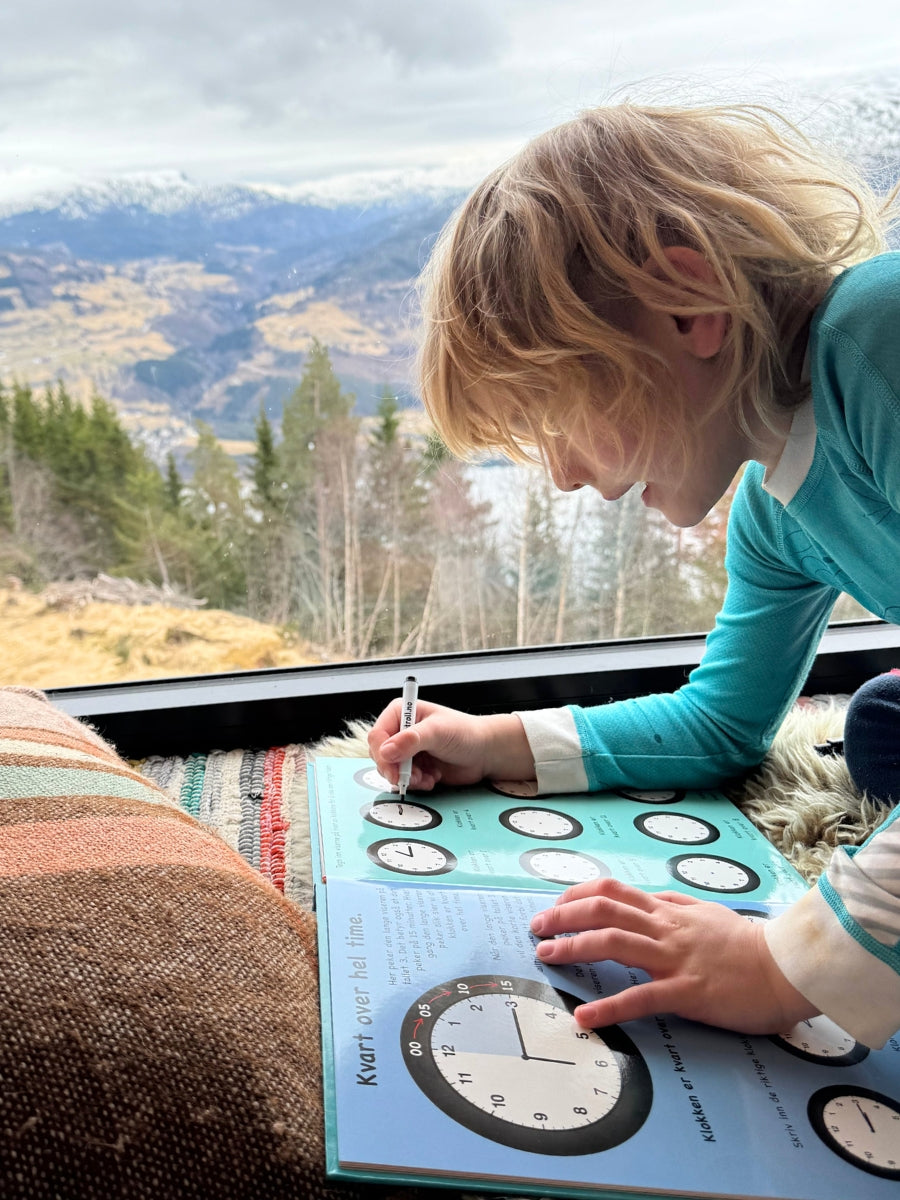 En gutt som øver på å lære klokken med Sjarmtroll.no sin klokkebok. Enkelt å lære klokken. Både digital og analog klokke.