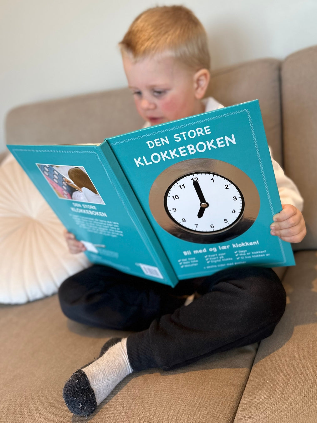 En gutt som leser klokkeboken. Bli med og lær klokken