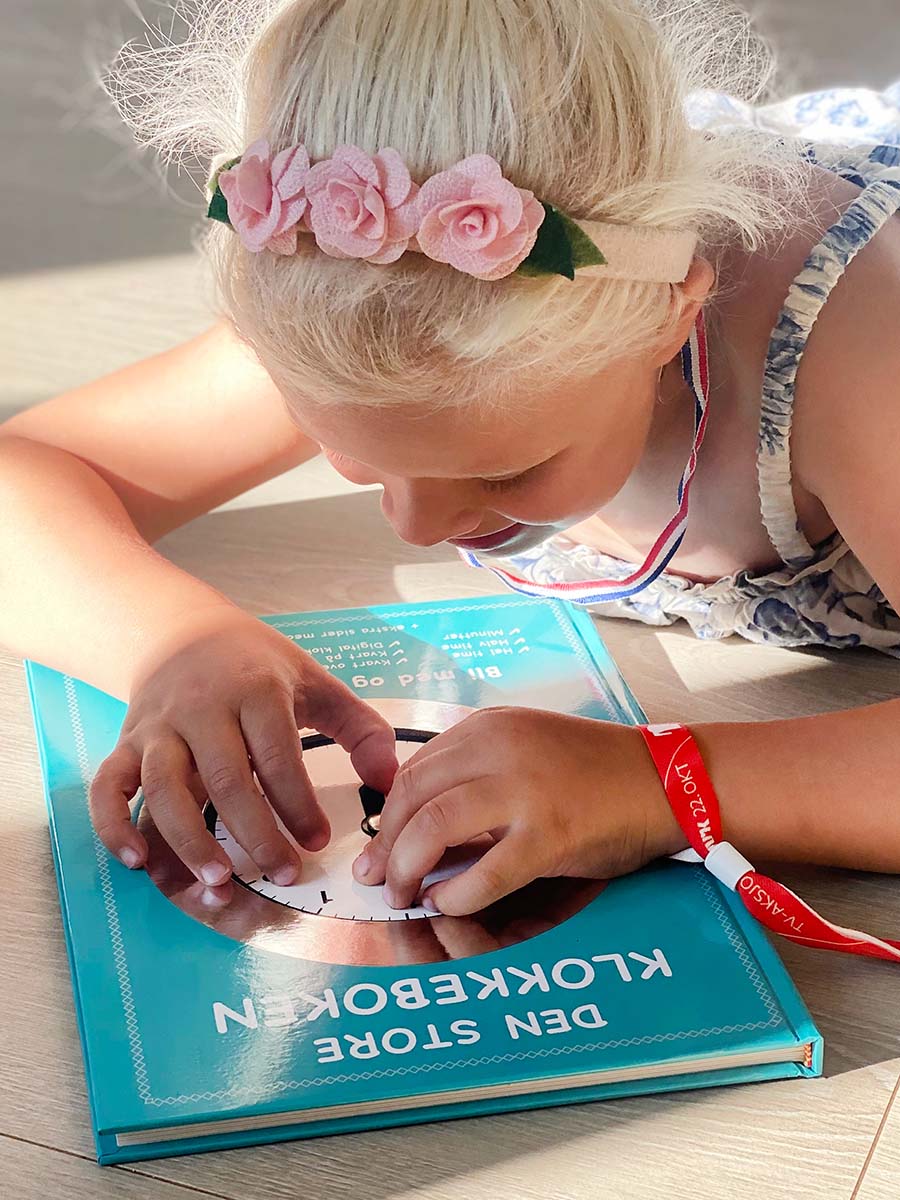 En jente som øver på klokken. Gjør det enkelt å lære klokken for barn.