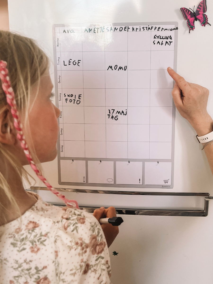 Mor og barn planlegger ukens aktiviteter med en magnetisk ukeplan