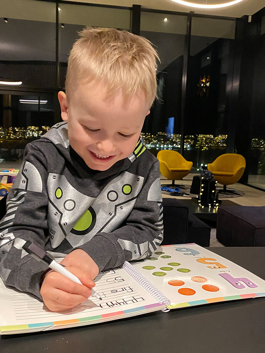 Gutt som skriver tall og bokstaver i en bok fra Sjarmtroll