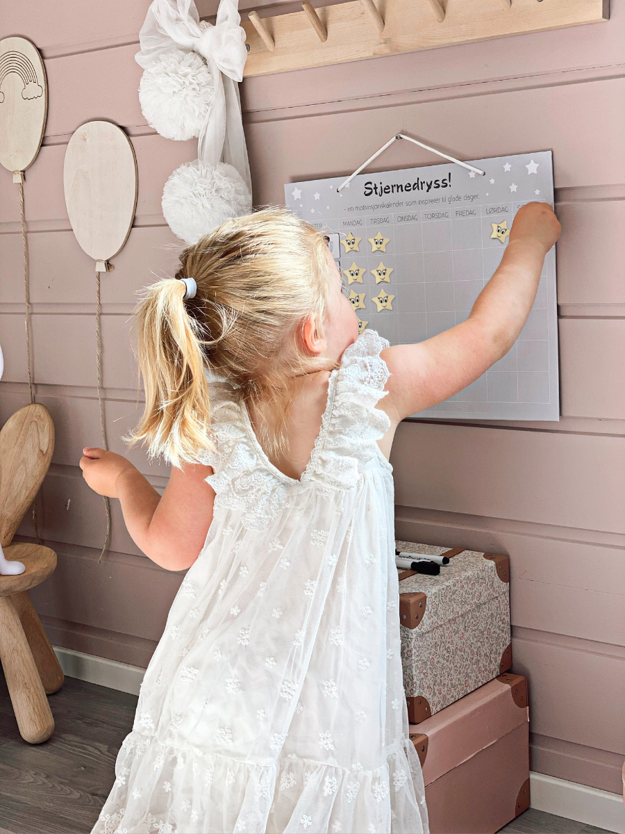 Jente som henger opp stjerner på Stjernedryss belønningstavle