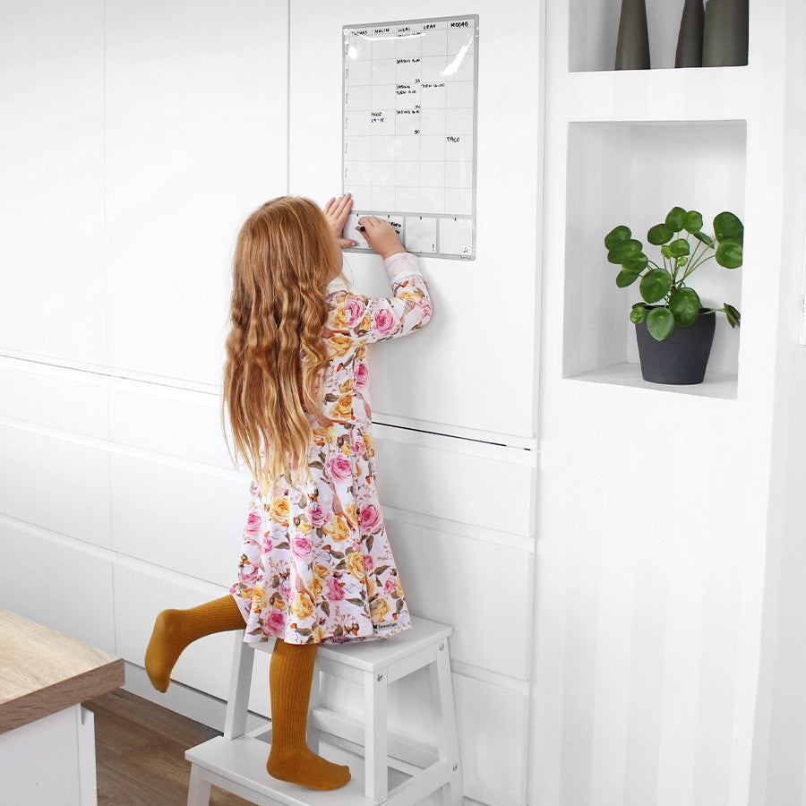 Barn som skriver på en magnetisk ukeplanlegger.