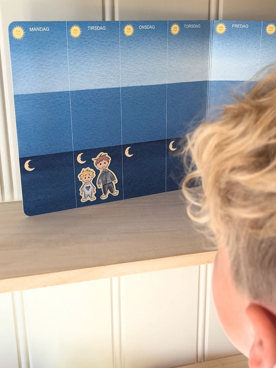 En liten gutt som ser på sin ukeplan laget il barn som bor litt hos mamma og litt hos pappa