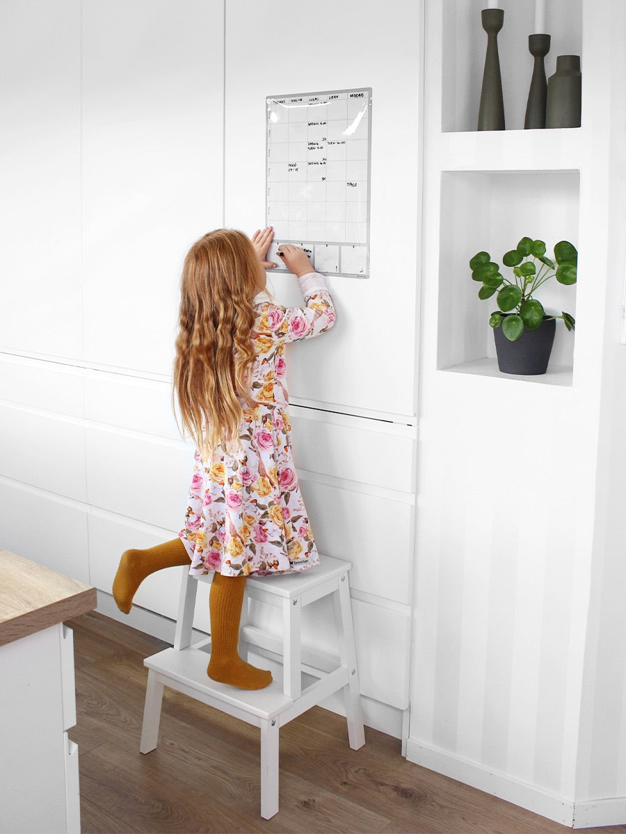 Barn som skriver på en magnetisk ukeplanlegger.
